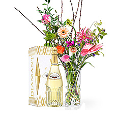 A bottle of Pommery champagne is accompanied by a beautiful bouquet with tropical, colorful flowers in a timeless vase.