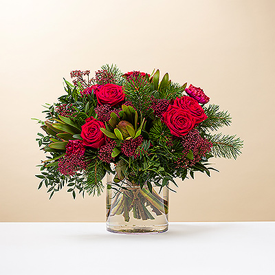 Wish them a very Merry Christmas with a beautiful red and green bouquet. Classic red roses and other blossoms are complemented with sprigs of pine and greenery is this festive Christmas flower arrangement.