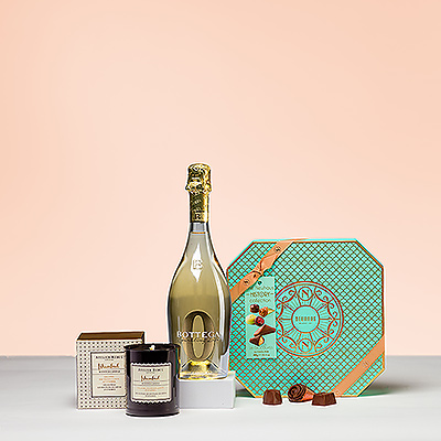 A gift basket with a fragrant scented candle, a bottle of delicious zero-alcohol bubbles and tasty Belgian chocolates is the ideal present for every bon vivant.