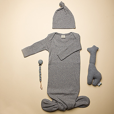 Welcome baby with this Mushie baby essentials gift set! This newborn gift includes an organic cotton knotted baby gown with matching beanie, food-grade silicone pacifier holder, and charming organic cotton giraffe rattle by Trixie. The breathable lightweight cotton baby gown will keep the little one comfy and cozy all night, with his favorite pacifier close by.