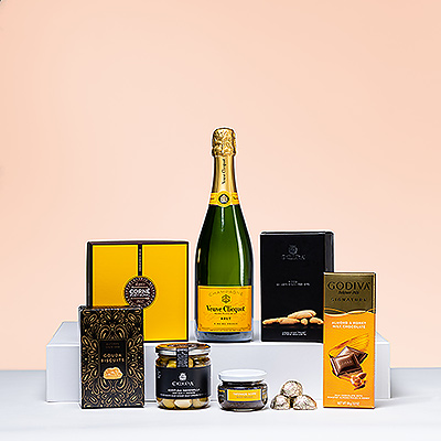 Este regalo de champán y aperitivos es una auténtica delicia. Descubra el maridaje perfecto del emblemático champán Veuve Clicquot Brut con chocolates belgas y aperitivos salados gourmet.