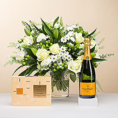 Tan brillante como un diamante centelleante, le presentamos este elegante ramo, todo en blanco. El ramo va acompañado de una botella del emblemático champán Veuve Clicquot y una caja de deliciosos bombones Carré de chocolate con leche Godiva, para una experiencia de regalo inolvidable.