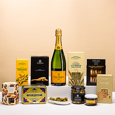 Para un regalo que combina las mejores marcas con una abundancia de ricos sabores, el Ultimate Gourmet Veuve Clicquot Summer Limited-Edition es la elección perfecta. Amigos, familiares y colegas disfrutarán de cada momento con esta suntuosa caja regalo, gracias a la generosa colección de deliciosos aperitivos maridados con el emblemático champán Veuve Clicquot.